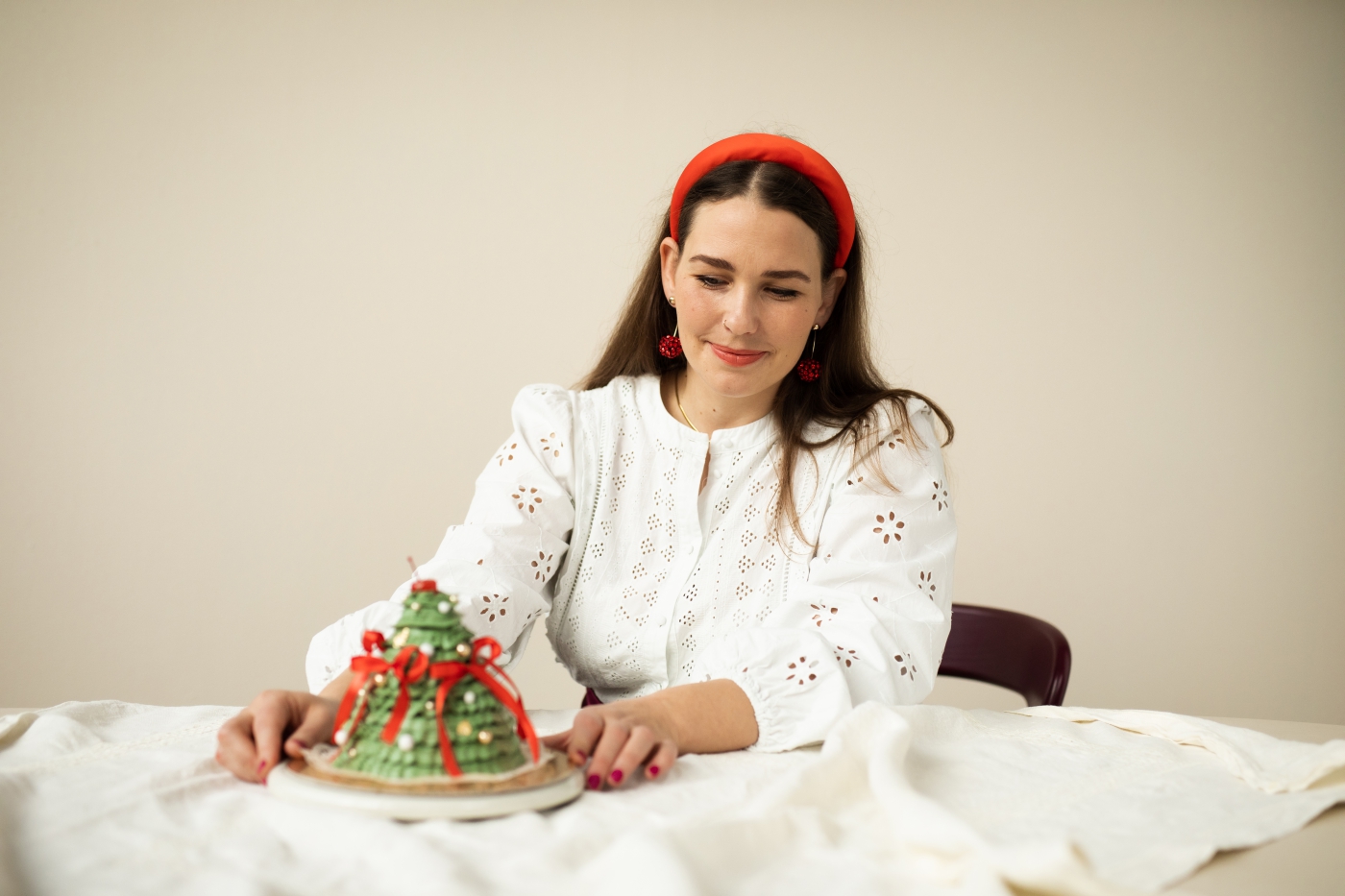 Porträt-Bäckerin-Pola-Held-Polz-Cakestudio-Torte-in Form-eines Weihnachtsbaums-mit-roten-schleifen-und -Perlen